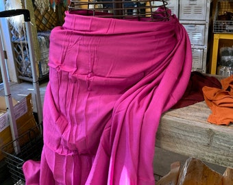 May include: A pink fabric wrap draped over a wire mannequin. The fabric is soft and flowing, with a subtle sheen. The wrap is a versatile piece that can be worn in a variety of ways.
