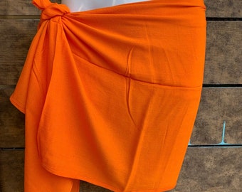 May include: A bright orange sarong tied around the waist. The sarong is made of a soft, lightweight fabric and is perfect for the beach or pool.