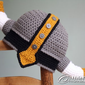 May include: Gray crocheted Viking hat with a yellow and black trim and white horns. The hat has gray buttons on the trim.