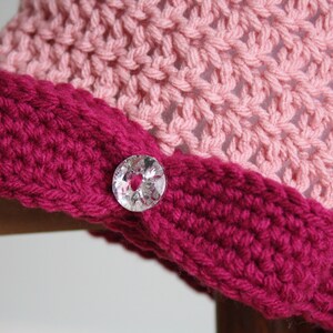 May include: A pink and burgundy crocheted hat with a clear button.