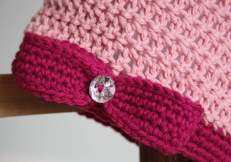 May include: A pink and burgundy crocheted hat with a clear button.