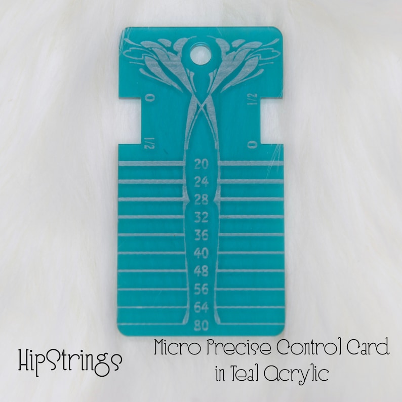 May include: A rectangular teal acrylic tool featuring a central hole at the top, engraved with horizontal lines and numerical markings ranging from 20 to 80, along with side notches labeled 0 and 1/2, designed for precise measurement and control.