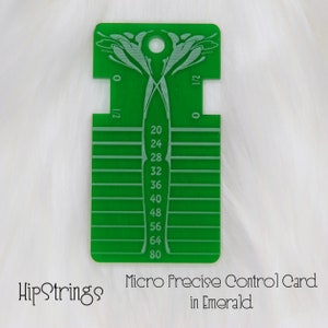 May include: A rectangular green acrylic control card featuring a top hole, decorative etched patterns, and a vertical scale with numerical markings from 20 to 80, alongside side notches labeled 0 and 1/2, with the text HipStrings Micro Precise Control Card in Emerald.