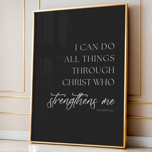 May include: Black framed wall art with gold trim. The artwork features white text on a black background. The text reads "I CAN DO ALL THINGS THROUGH CHRIST WHO strengthens me" and "Philippians 4:13".