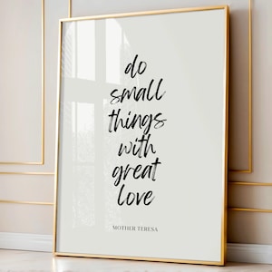Puede incluir: Un estampado enmarcado con un marco dorado. El estampado presenta la cita "do small things with great love" en letras negras con pincel, atribuida a la Madre Teresa, sobre un fondo gris claro.