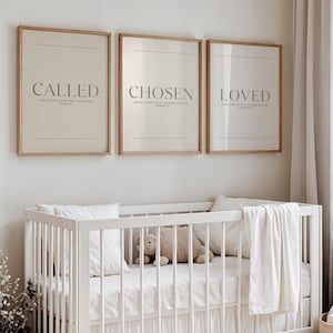Könnte beinhalten: Drei gerahmte Drucke mit den Wörtern "CALLED", "CHOSEN" und "LOVED" in grauer Schrift. Die Drucke haben einen hellbeigen Hintergrund und sind in hellbraunen Holzrahmen. Im Vordergrund befindet sich ein weißes Kinderbett mit Bettwäsche und einem Stoffbären.