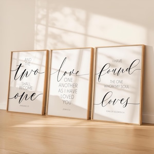 Puede incluir: Tres impresiones artísticas enmarcadas con citas inspiradoras en elegante escritura negra sobre un fondo blanco. Los marcos son de color madera clara. Las citas incluyen "Y los dos serán uno", "Amaos los unos a los otros como yo os he amado", y "He encontrado a aquel a quien mi alma ama."