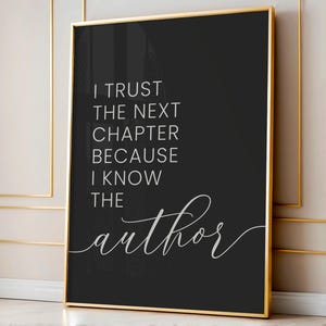 May include: A framed black and white print with the quote, "I trust the next chapter because I know the author." The text is in a mix of a serif and cursive font. The frame is gold.