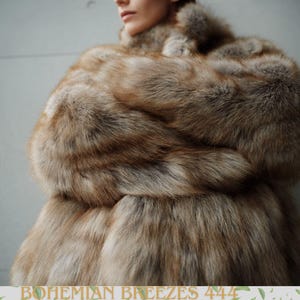 May include: A luxurious brown and tan fur coat with a high collar. The coat has a plush texture and a natural color gradient. The text "BOHEMIAN BREEZES 444" is at the bottom of the image.