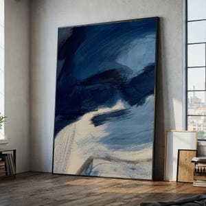 Pode incluir: Uma grande peça de arte de parede retangular com pinceladas abstratas em tons de azul marinho profundo, azul ardósia e branco sujo. A pintura está inserida numa moldura preta fina, exibindo texturas de tinta em camadas que criam movimento.