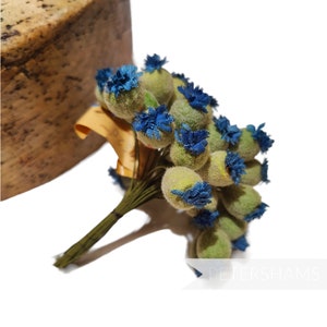 May include: A bouquet of blue and green artificial flowers. The flowers are made of fabric and have a fuzzy texture. The bouquet is tied together with a brown ribbon.