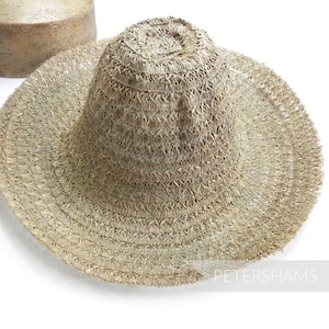 May include: A wide-brimmed straw hat with a woven texture. The hat is light brown in color and has a slightly rounded crown.