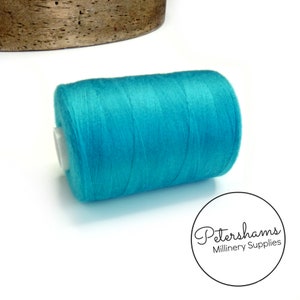 以下が含まれることがあります： 縫製やクラフトプロジェクト用のターコイズ色の糸の糸巻き。糸は白いプラスチック製の糸巻きにしっかりと巻かれています。