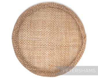 May include: A round, beige, woven hat base made of straw. The base is a blank canvas for millinery creations.