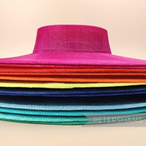 May include: A stack of colourful, wide-brimmed hats made of woven straw. The hats are arranged in a rainbow pattern, starting with a bright pink hat at the top and ending with a green hat at the bottom.