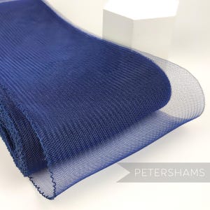 May include: A roll of dark blue tulle fabric. The fabric is soft and sheer, with a fine mesh weave. It is perfect for crafting, decorating, and adding a touch of elegance to any project.