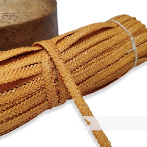 May include: A roll of woven straw trim in a light orange colour. The trim is approximately 1.2 cm wide and is perfect for adding a rustic touch to crafts and home decor projects.