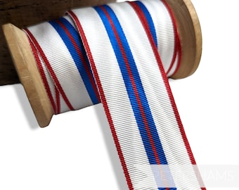 May include: A spool of white ribbon with red and blue stripes. The ribbon is wound around a wooden spool.
