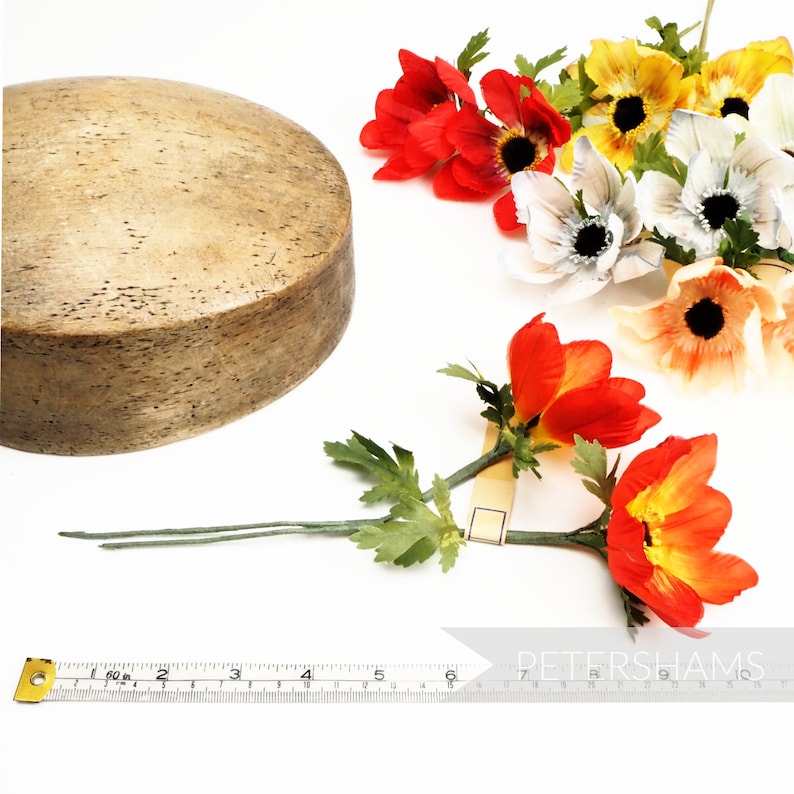 May include: A wooden round base with a light brown finish and a set of artificial flowers with red, orange, white, and yellow petals. The flowers are arranged in a bouquet with green leaves.