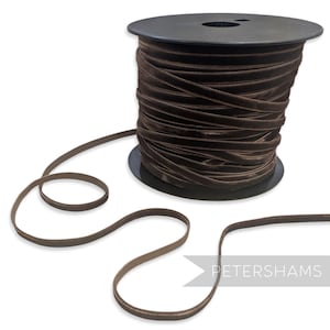 May include: A dark brown velvet ribbon on a black spool. The ribbon is unwound, showing its texture. The word "PETERSHAMS" is visible in white text on the right side of the image.