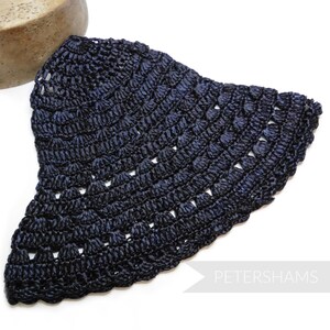 May include: A dark blue crocheted hat with a wide brim. The hat is made of a fine, delicate yarn and has a scalloped edge.