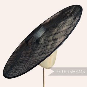 Peut inclure: Un grand chapeau noir à larges bords avec une couronne structurée, présenté sur une tête de mannequin. Le chapeau a une texture tissée et une apparence sombre et élégante. Le chapeau est adapté aux occasions spéciales.