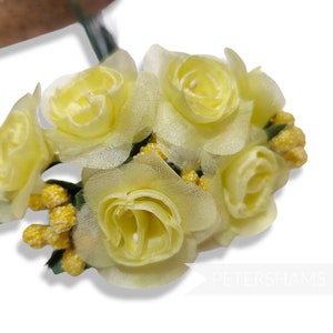 May include: A bunch of pale yellow silk roses with yellow centres. The roses are arranged in a cluster and have a delicate, soft texture.