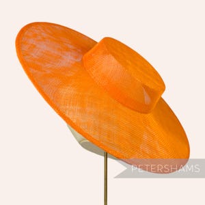 May include: A large, bright orange, wide-brimmed hat made of a woven material. The hat has a flat crown and a wide, floppy brim.