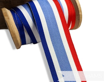 May include: Red, white, and blue striped ribbon wound around a wooden spool. The ribbon is approximately 1 inch wide.