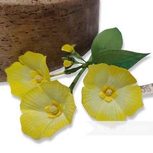 May include: Three yellow silk flowers with green stems and leaves. The flowers have a white center and are arranged in a cluster.