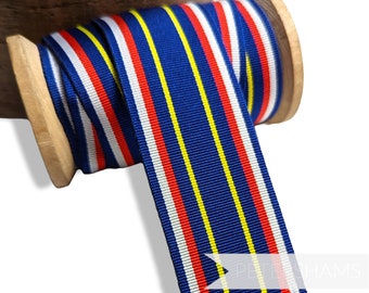 May include: A spool of blue, white, red, and yellow striped ribbon. The ribbon is wound around a wooden spool.