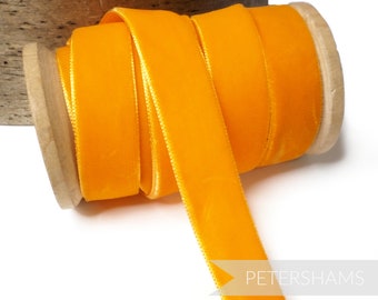 Könnte beinhalten: Eine Spule mit leuchtend orangefarbenem Samtband. Das Band ist um eine Holzspule gewickelt.