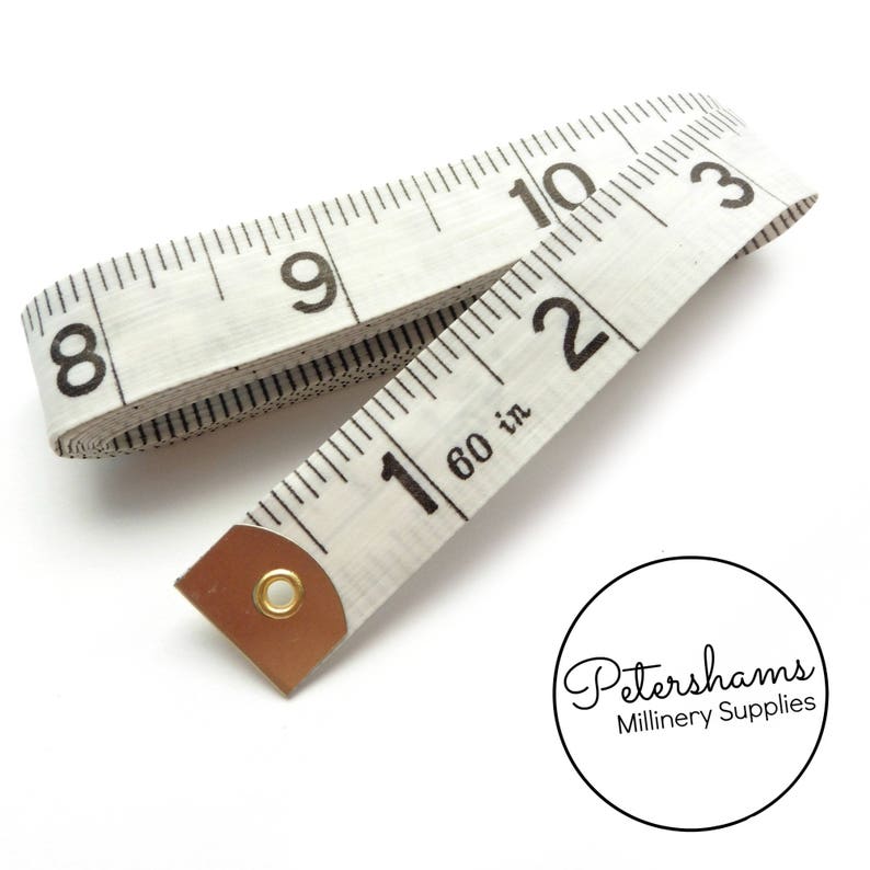 May include: White fabric measuring tape with black markings, numbered 8 through 10 and 1 through 3. The tape is rolled up and has a brass end cap. The text "1 60 in" is printed on the tape.