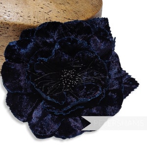 May include: A large, navy blue velvet flower with a detailed center. The flower is made of multiple layers of petals and has a textured, velvety surface.