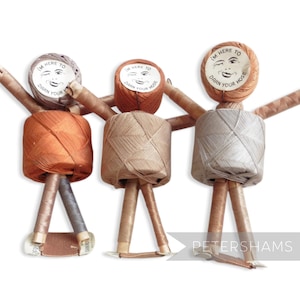 May include: Three spools of thread with faces and the text "I'm here to darn your hose" on the labels. The spools are orange, beige, and silver.