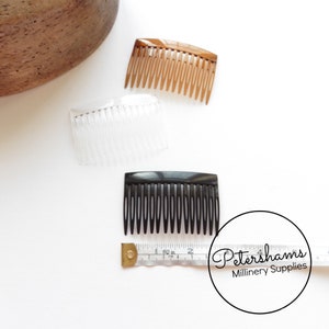 May include: Three plastic hair combs in different colors: brown, clear, and black. The combs are approximately 2 inches long and have a rectangular shape. The combs are arranged on a white surface with a measuring tape.