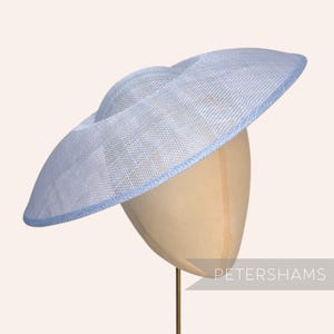 May include: A light blue, wide-brimmed hat with a matching blue trim. The hat is displayed on a mannequin head. The hat has a woven texture and a slightly curved brim. The hat is a stylish accessory.