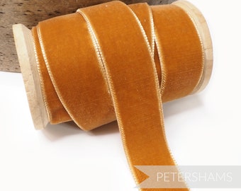 Könnte beinhalten: Eine Spule mit goldenem gelbem Samtband mit einem dezenten Glanz. Das Band ist um eine Holzspule gewickelt und hat einen weißen Rand.