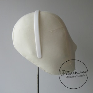 May include: White plastic headband for millinery, shown on a white millinery head form. Petershams Millinery Supplies.