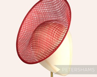 以下が含まれることがあります： マネキンの頭に展示された、織り目加工の赤い広いつばの帽子。 帽子は濃い赤色のトリムとわずかに傾斜したデザインが特徴です。 「PETERSHAMS」の文字が画像に表示されています。