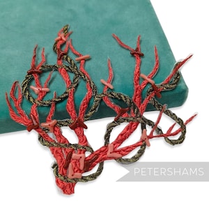 May include: An embroidered coral reef design in red, gold, and brown, with small pink accents. The design is placed on a teal green velvet surface. The word "PETERSHAMS" is visible in the lower right corner.