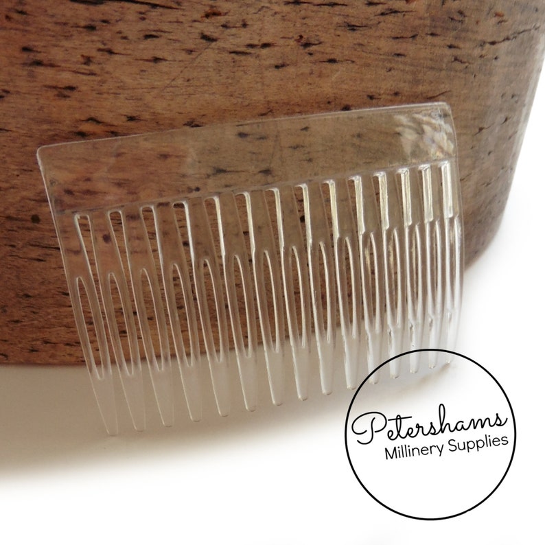 May include: A clear plastic comb with a rounded edge. The comb has 18 teeth and is approximately 2 inches long.