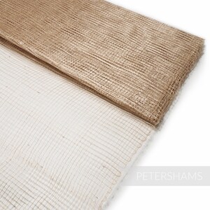 May include: Two pieces of brown and white mesh fabric. The fabric is woven with a grid pattern. The fabric is folded in half and the top layer is slightly darker than the bottom layer.