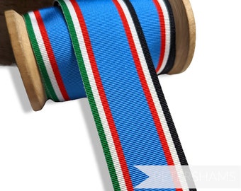 May include: A spool of blue, red, white, green, and black ribbon. The ribbon is wound around a wooden spool.