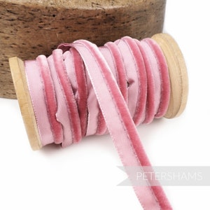 Könnte beinhalten: Eine Spule mit rosafarbenem Samtband mit Satinrand. Das Band ist um eine Holzspule gewickelt.