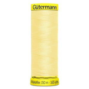 May include: A spool of pale yellow Gütermann Maraflex thread. The top and bottom yellow labels feature the brand name Gütermann and the text Maraflex 150 m - 165 yds. The thread is wound tightly around the cylindrical spool in a cross-hatch pattern.