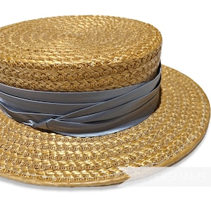 May include: A straw boater hat with a wide brim and a gray ribbon. The hat is made of woven straw and has a light brown color.