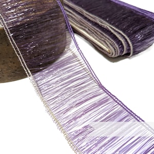 Peut inclure: Garniture de frange iridescente violette avec un fil métallique argenté le long du bord. La frange est faite de fines brins de tissu délicats.