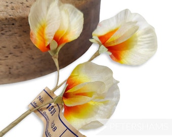 May include: Three delicate silk flowers with white petals and orange and yellow centers. The flowers are attached to thin brown stems and have a vintage feel. The flowers are labeled with a tag that reads "No. 1331, Made in Geneva, 1338, Public."