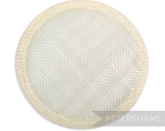 May include: A round, cream-colored hat base made of sinamay straw with a woven texture. The base is approximately 4 inches in diameter.